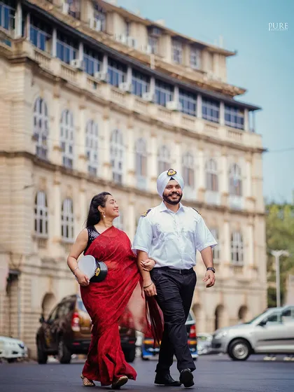 Anchored in love, Kanwaldeep and Avneet walk arm-in-arm through the streets of Colaba. His merchant navy uniform and her elegant red saree create a beautiful contrast against the old-world architecture of Mumbai.