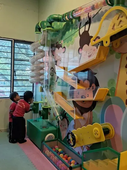 Two young explorers working together at our interactive ball wall. It's a great activity for cooperative play and problem-solving.