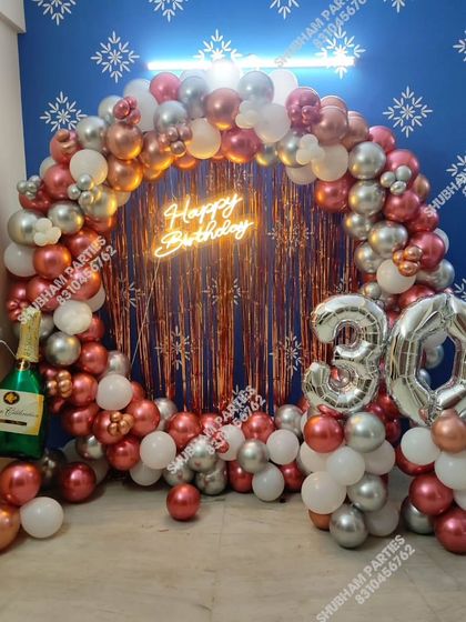 A glamorous 30th birthday celebration featuring a rose gold and silver balloon ring with a fringe backdrop and large number balloons.