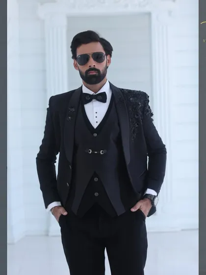 A confident pose in our custom black embroidered tuxedo. The three-piece set includes a matching waistcoat and is tailored to provide a sharp, commanding presence.