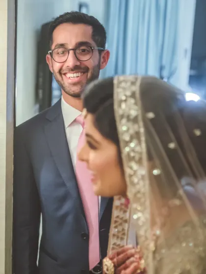 A candid shot capturing the groom's happy expression as he sees his bride. These "first look" moments are filled with genuine emotion and make for unforgettable photos.