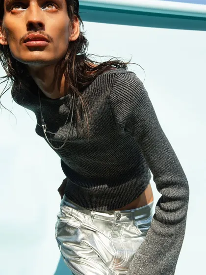 A close-up from the Myntra FWD shoot, focusing on the texture of the knitwear and the metallic sheen of the pants. The bright, direct sunlight creates sharp shadows and highlights the details of the clothing.