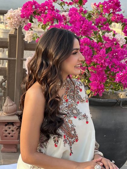 The bride smiling against a backdrop of bougainvillea, her soft waves looking natural and beautiful.