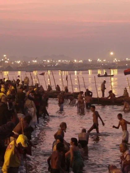 Devotees taking a holy dip in the river at dusk during the Kumbh Mela. The atmosphere is filled with spirituality day and night.