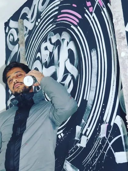 A photo of me during the creation of the 30-foot office mural. The monochrome calligraffiti background was a physically demanding part of the process.