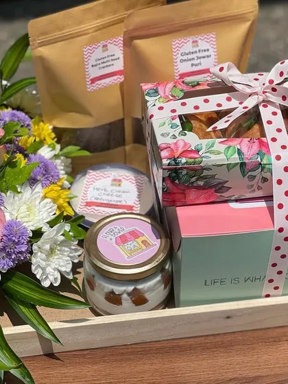 This elegant hamper combines my baked goods with healthy snacks. It includes a box of savoury puffs, a jar of my dessert tubs, and packs of gluten-free onion sesame crisps, along with a beautiful bouquet.