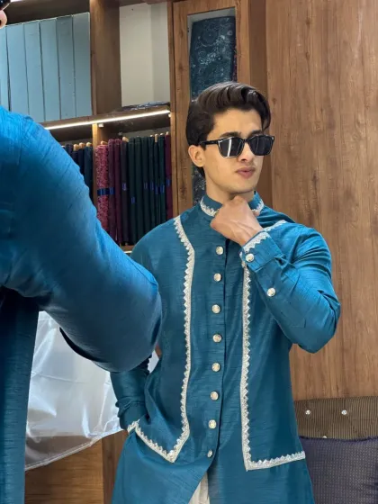 A client looking sharp in a custom blue Indo-Western outfit. The white detailing on the jacket adds a crisp, elegant contrast, making it perfect for weddings.