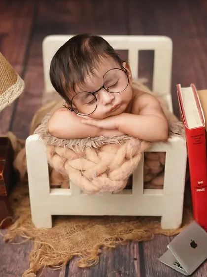 A different angle of the 'tiny scholar' theme, showing the baby sleeping soundly in his miniature bed, surrounded by books.