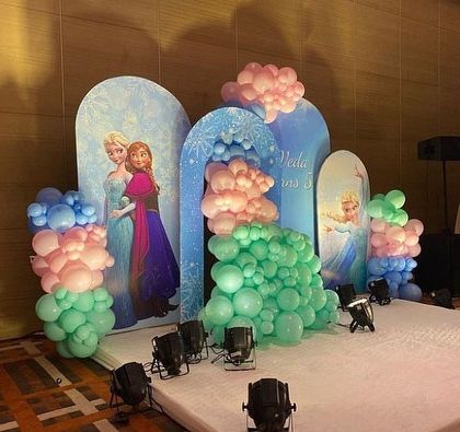 Let it go with a magical Frozen-themed birthday party. This stage setup uses multiple arched backdrops featuring Elsa and Anna, with balloon decorations in icy blue, green, and pink to recreate the enchanting world of Arendelle.