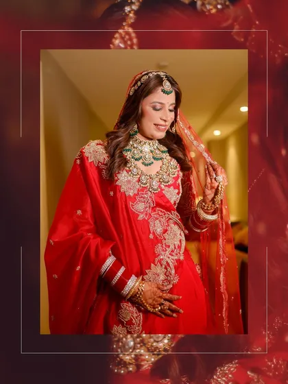 The bride adjusts her veil in a moment of quiet grace, her red and gold lehenga creating a stunning visual.