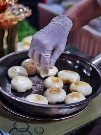 How 'bao' you? Here, my chef is pan-frying soft bao buns until they are perfectly golden brown, ready to be filled with deliciousness.