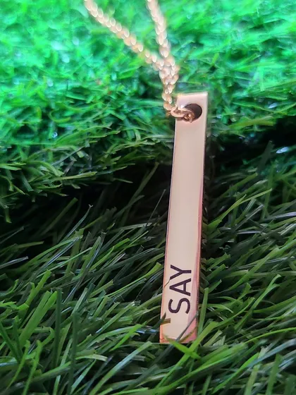 A rose gold bar pendant engraved with an inspirational word. This demonstrates that the engravings can be more than just names, but also reminders of personal mantras.