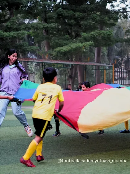 A coach joins in on the parachute game, making training fun and building a strong connection with the players.