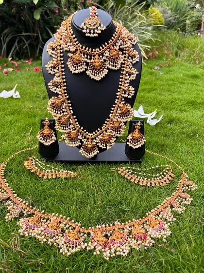 Here is a complete bridal set with pearl and kemp stone detailing, laid out to show you everything that's included. You get the choker, haaram, vaddanam, bajuband, and matching earrings for a fully coordinated look.