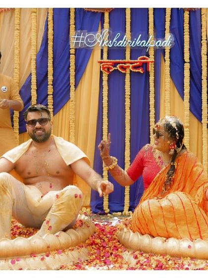 The couple sits in large brass tubs, ready for the main event of the Haldi ceremony, smiling in anticipation.