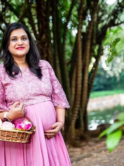 A lovely solo portrait of the mom-tobe in a pink dress, holding a basket of flowers and glowing with happiness.