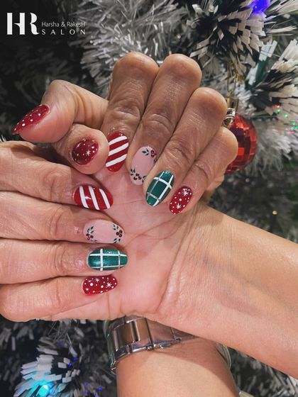 A cozy and festive Christmas manicure. This design features a mix of patterns, including red and white stripes, green plaid, and red glitter, just like a Christmas sweater.