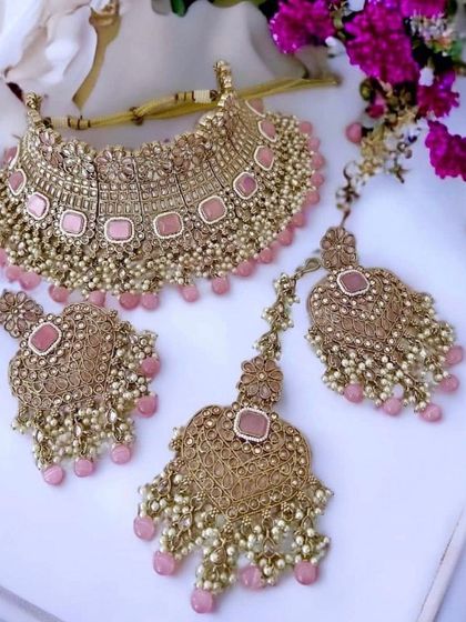 An antique-style pink polki crystal bridal set, including a choker, earrings, and maang tikka.