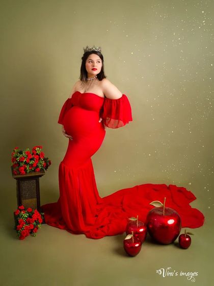 A fairytale comes to life with this Snow White inspired theme. The vibrant red gown, poison apples, and regal pose create a fun and highly creative maternity portrait.