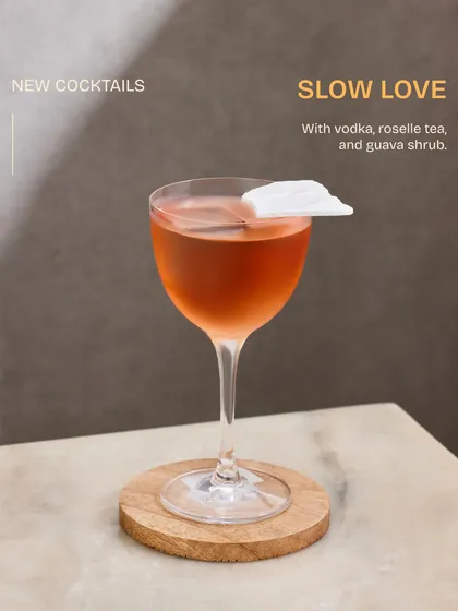A study in elegance, the Slow Love cocktail. The delicate rice paper garnish floats atop a blend of vodka, roselle tea, and guava shrub, creating a visually stunning and romantic drink.