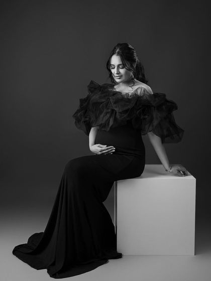 A seated solo portrait in black and white, looking regal and serene.
