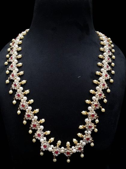 A long necklace or 'haar' made with ruby-colored stones and pearls. This classic combination is timeless and adds elegance to any saree or traditional dress.