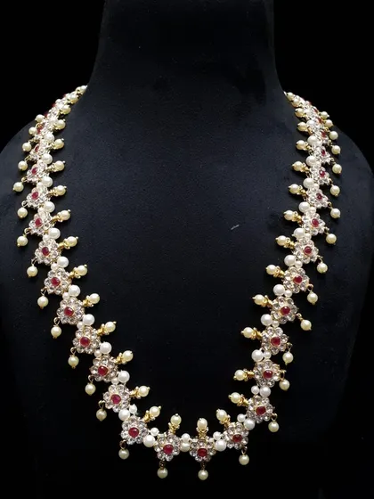 A classic long necklace made with ruby-colored stones and pearls. This type of haar is timeless and adds a touch of elegance to any saree or traditional dress.