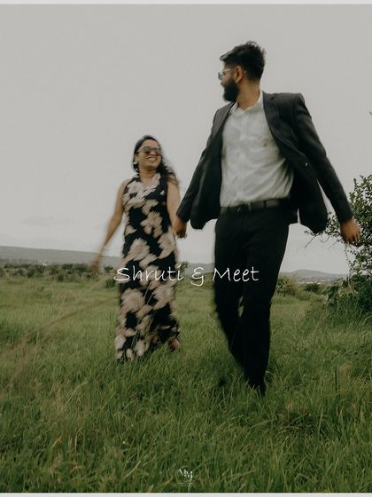 A candid shot of the couple walking and laughing in a field. This image captures the simple joy and happiness of their journey together.