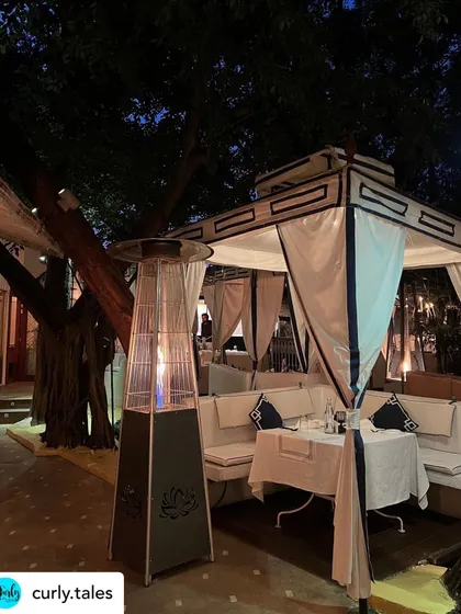 The warm glow of the heater and the soft lighting of the cabana create a cozy and inviting atmosphere for a winter dinner.