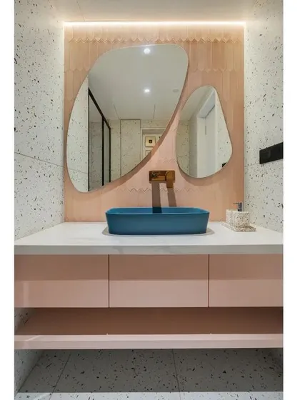 This bathroom combines playful and organic elements. I used terrazzo-style tiles and a soft pink vanity for a touch of modern fun, contrasted with a bold blue vessel sink. The organically shaped mirrors add a sculptural and artistic feel to the space.