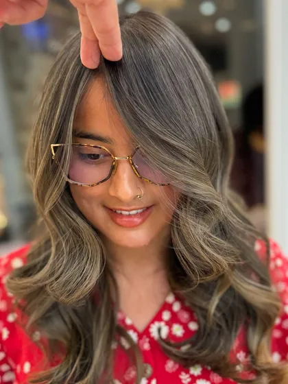 A happy client showing off her new ash blond hair, a perfect example of a cool-toned look.