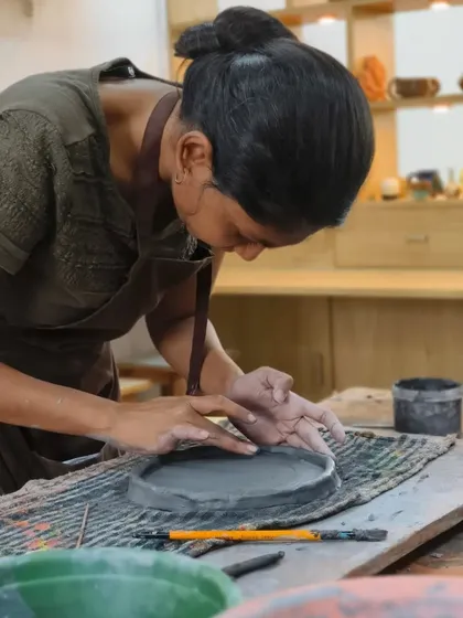 A student works on a hand-built plate, carefully smoothing the edges. This is a regular day at the academy, filled with the quiet hum of creativity and focused work.