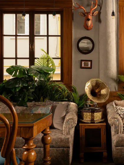 A vintage gramophone sits between two plush armchairs, ready to fill the room with music. These curated objects are not just decor; they are storytellers that contribute to the café's timeless charm.