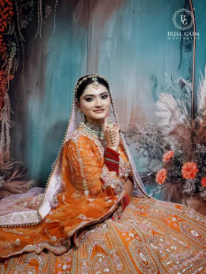 Seated gracefully, this bride looks like a painting. Her orange lehenga fills the frame, and her soft makeup look with a traditional 'maang tikka' completes this picturesque moment.