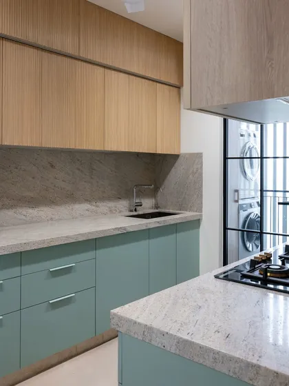 This kitchen combines a refreshing mint green with the natural warmth of fluted wood. The soft pastel hue of the lower cabinets provides a gentle pop of color, while the wooden upper cabinets and stone countertop keep the space feeling grounded and balanced.