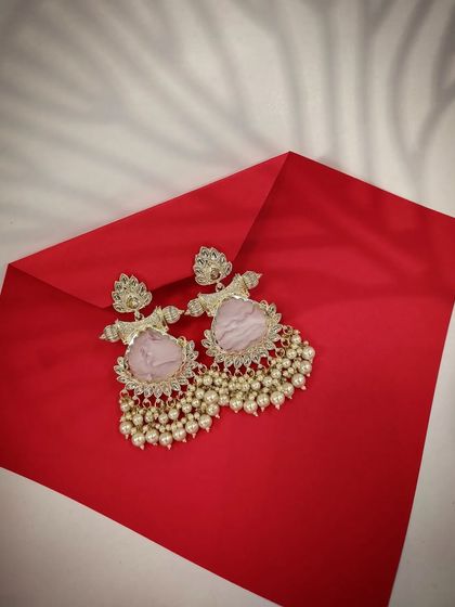 A product shot of the contemporary drop earrings in a lovely pink shade, presented on a red envelope for a festive feel.