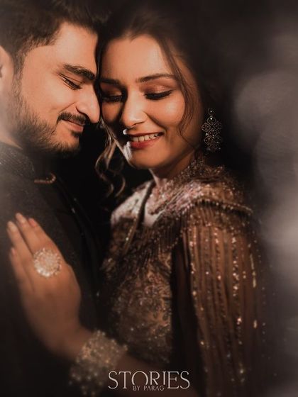 A dreamy, soft-focus portrait of a couple on their Sangeet night. The blurred lights and their gentle embrace create a romantic and intimate atmosphere, capturing the magic of the celebration.