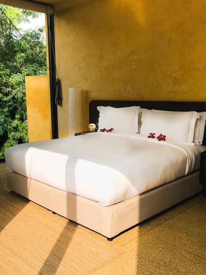 Sunlight streams into this suite, highlighting the clean lines of the bed and the warm, textured flooring.