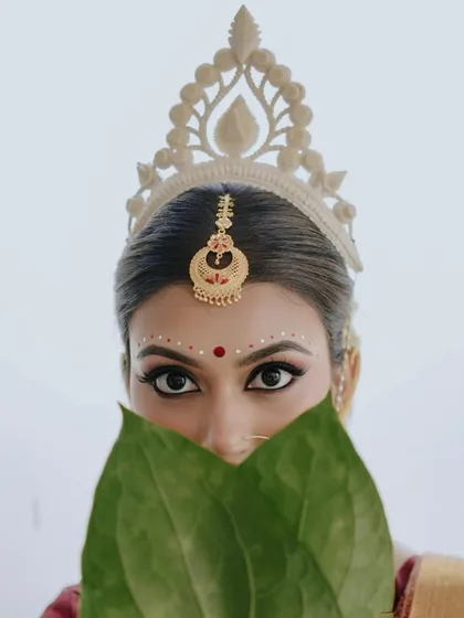 There is a unique poetry to Bengali bridal traditions. For my bride Archita, we focused on the iconic elements: the expressive kohl-lined eyes, the intricate bindi art, and the radiant glow, all framed by the betel leaves during the Shubho Drishti ritual.