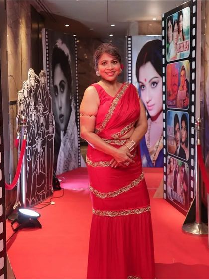 The birthday girl, Asha, looking radiant in her red sari, posing along the movie poster walkway.