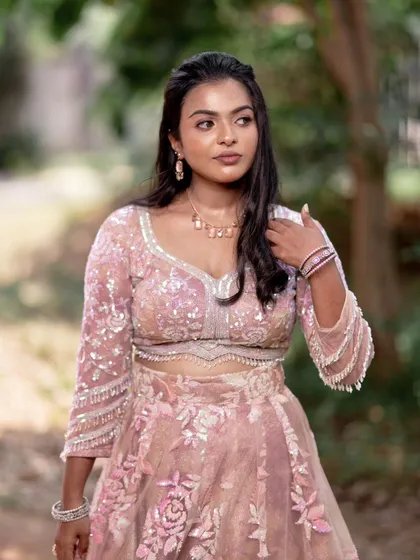 A model posing in a pink lehenga, showing off a subtle yet glamorous makeup look perfect for a reception.