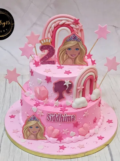 A pretty two-tier Barbie-themed cake for a second birthday. This pineapple cake is decorated in shades of pink with Barbie silhouettes, rainbows, and stars.
