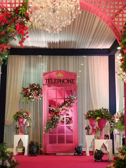 A quirky photo booth idea: a classic British telephone box, painted pink and adorned with flowers to match the event's theme.