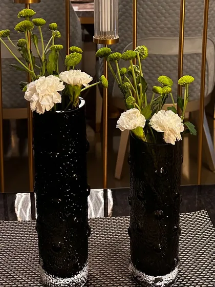 Modern black textured vases with simple arrangements of white and green carnations. A minimalist yet chic detail for a contemporary home event.