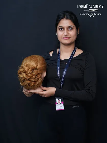 A proud student displaying her work on a mannequin. We celebrate our students' progress as they master complex styles like this braided bun.