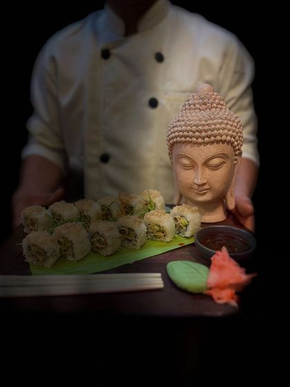 The dramatic lighting in this shot highlights the careful artistry that goes into every platter we create. Our chef holds the sushi platter, ready to be served to delighted guests.