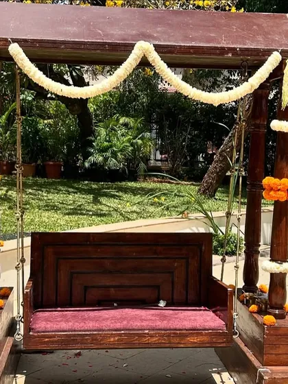 A beautifully decorated traditional wooden swing (oonjal) with simple jasmine and marigold garlands, perfect for a pre-wedding ceremony or photoshoot.