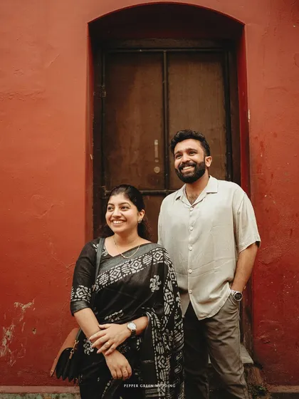 A relaxed portrait against a vibrant red wall in Fort Kochi, showcasing the unique colors and textures of the historic location.