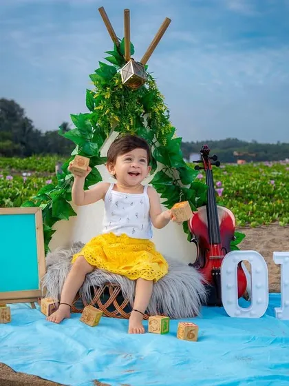 An outdoor first birthday photoshoot with a fun, bohemian teepee setup. This session combines the beauty of a natural beachside field with celebratory props for a unique and joyful portrait.
