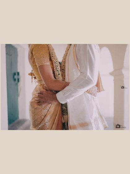 An intimate, faceless portrait focusing on the couple's embrace, highlighting the texture of their traditional outfits.